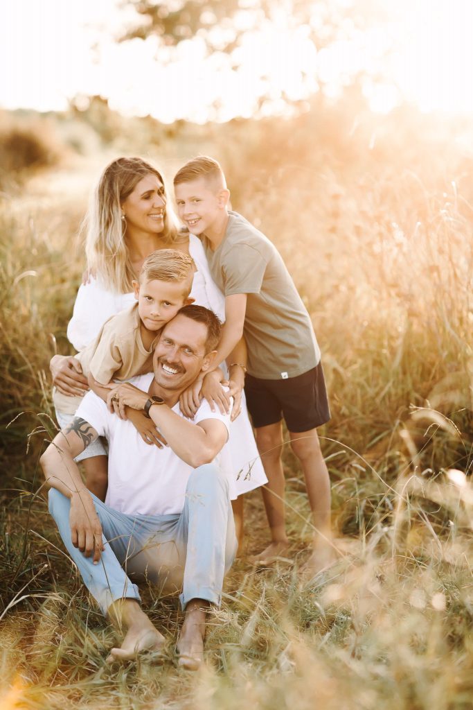 Family of four cuddling in long grass